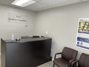Black front desk, with two brown chairs, a poster and the clinic's logo
